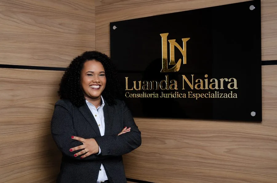 Dra. Luanda Naiara — Presidente da Comissão de Direito Administrativo, OAB 29ª Subseção, ao lado do letreiro do escritório